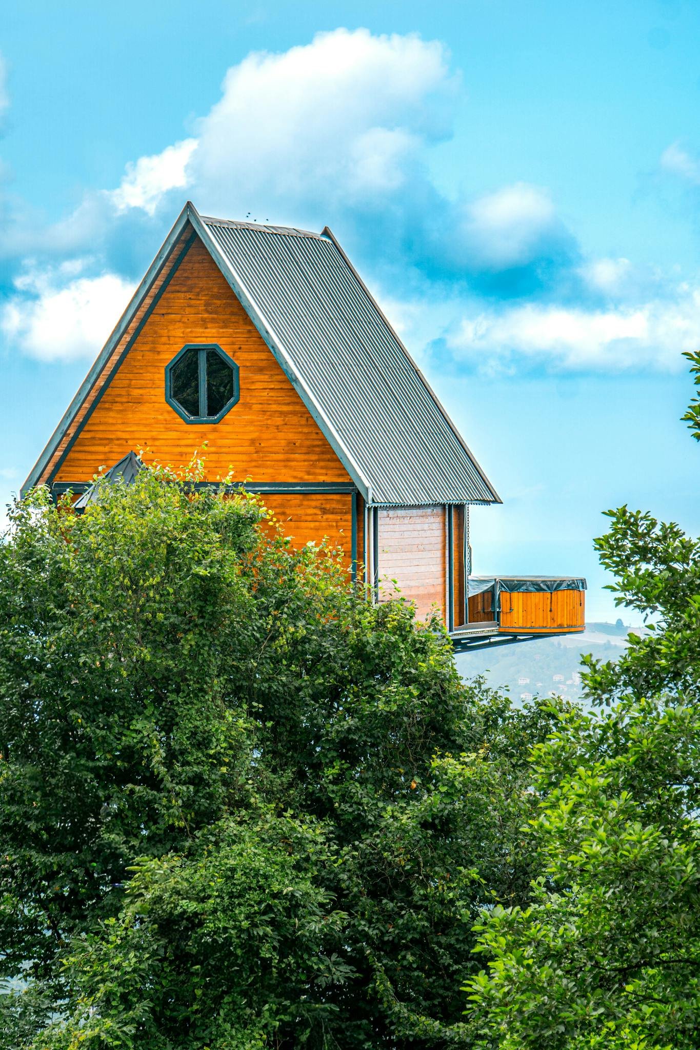 A picturesque A-frame cabin surrounded by trees against a blue sky.