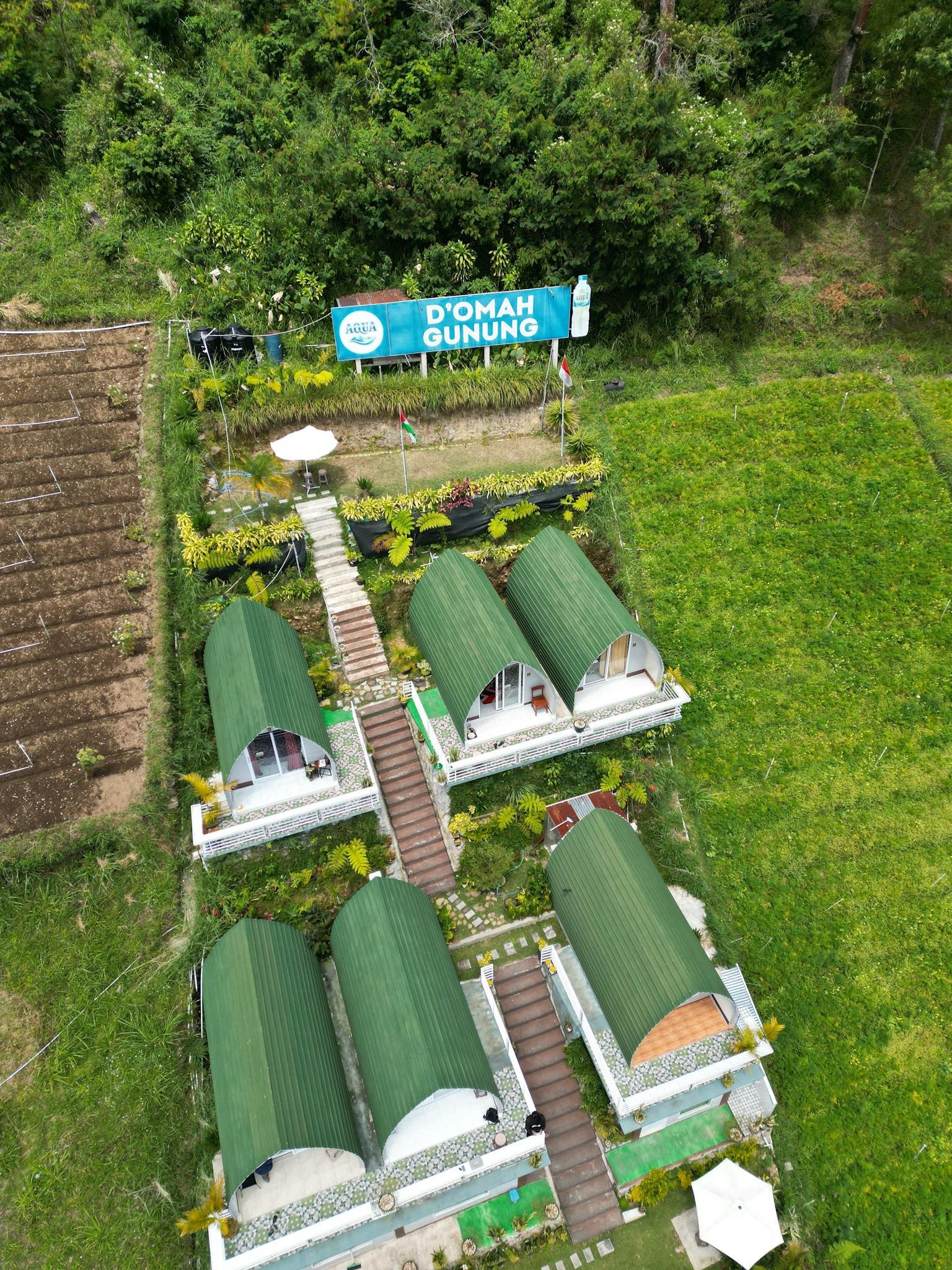 Aerial shot of a green-roofed cabin retreat in a lush, forested area.
